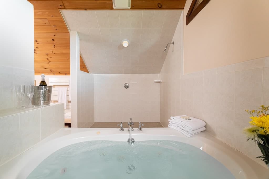 A modern bathroom featuring a jacuzzi tub, decorative towels, and a bottle of champagne.