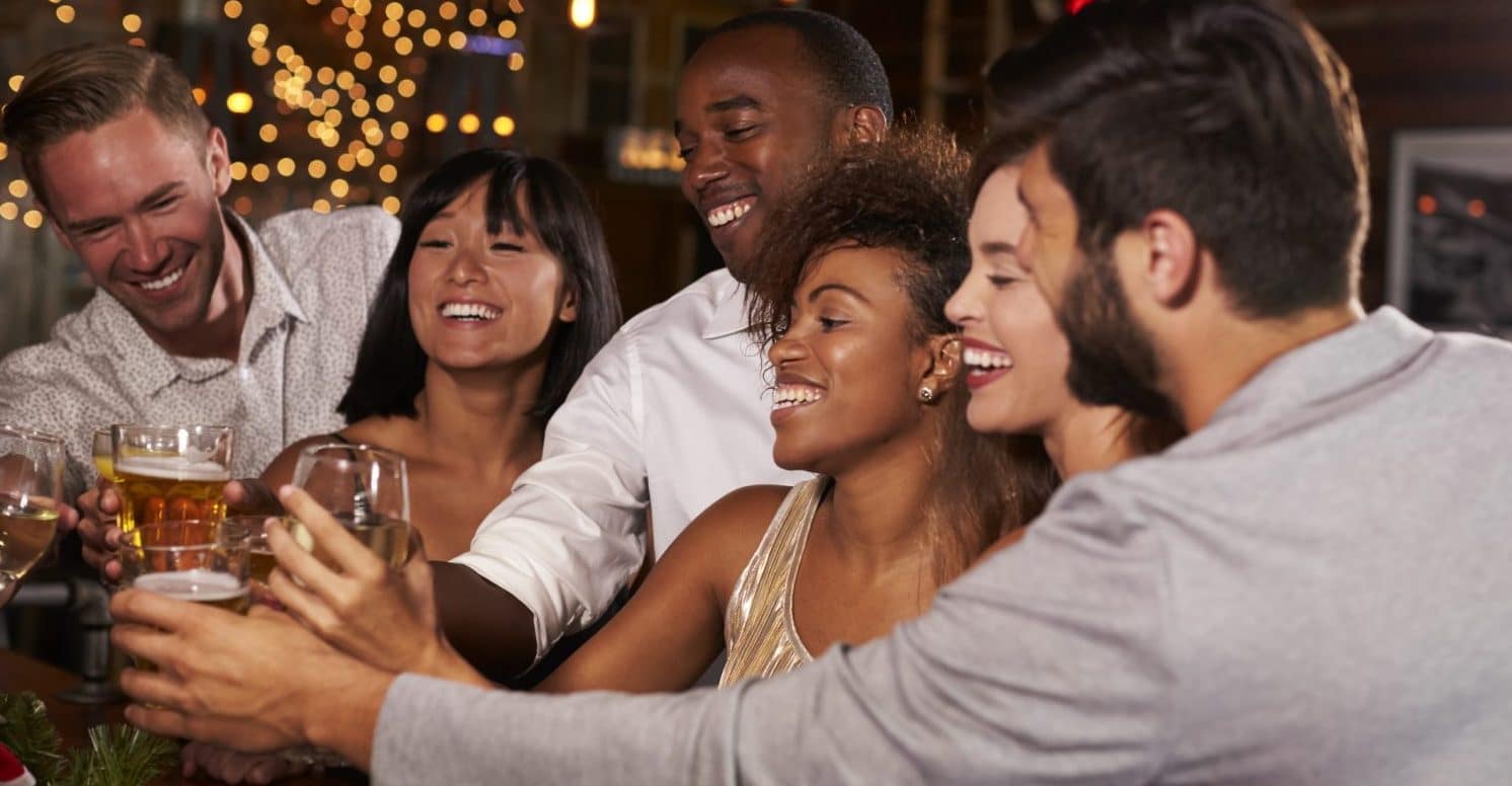A group of six friends joyfully clinking glasses while celebrating together.