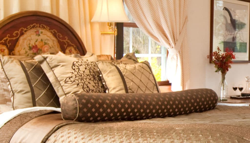 Elegant bedroom featuring a beautifully made bed with decorative pillows and a cozy ambiance.