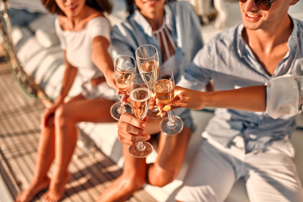 A group of three people clinking champagne glasses together on a yacht.