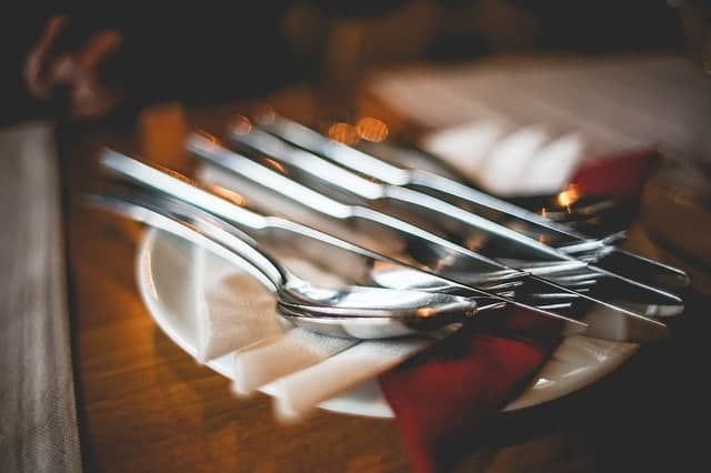 A close-up of metallic cutlery arranged on a white plate with folded napkins.