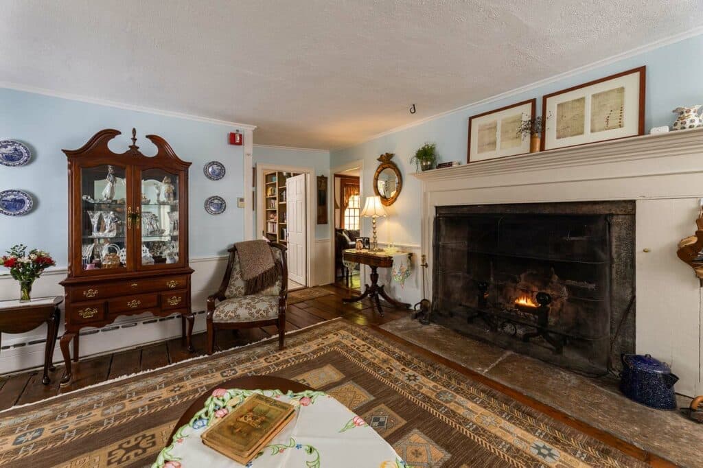 A cozy living room featuring a fireplace, antique furniture, and decorative accents.