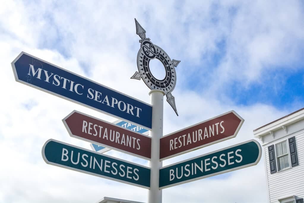 A directional signpost indicating various locations including Mystic Seaport, restaurants, and businesses.