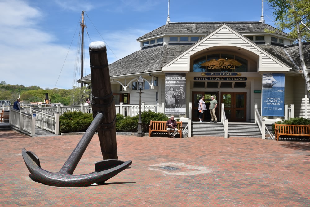 A large anchor sculpture stands in front of a waterfront visitor center.