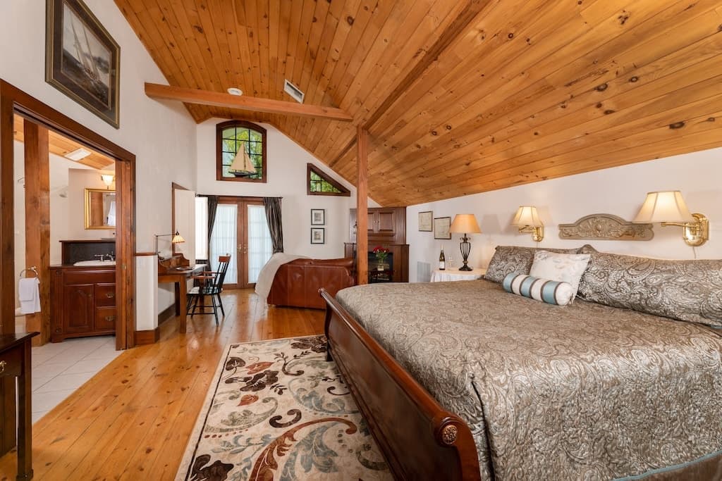 A cozy bedroom with a wooden ceiling, a large bed, and tasteful decor.