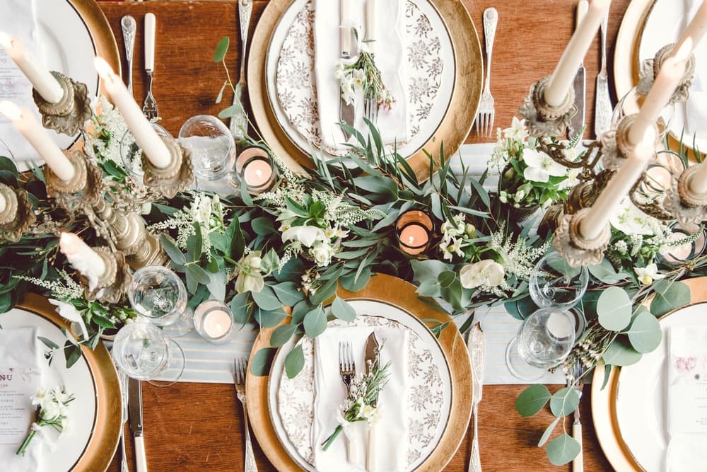 An elegantly set dining table adorned with floral arrangements, candles, and decorative plates.