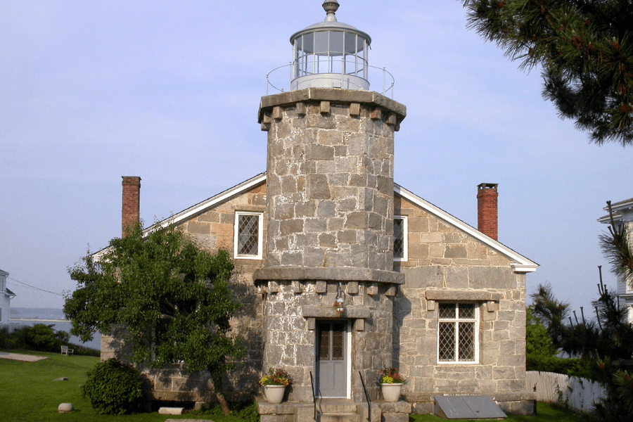 A stone lighthouse-style house with a circular tower and a lantern room at the top.