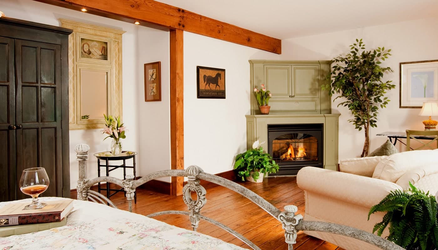 A cozy, softly lit living space featuring a fireplace, plants, and comfortable furniture.