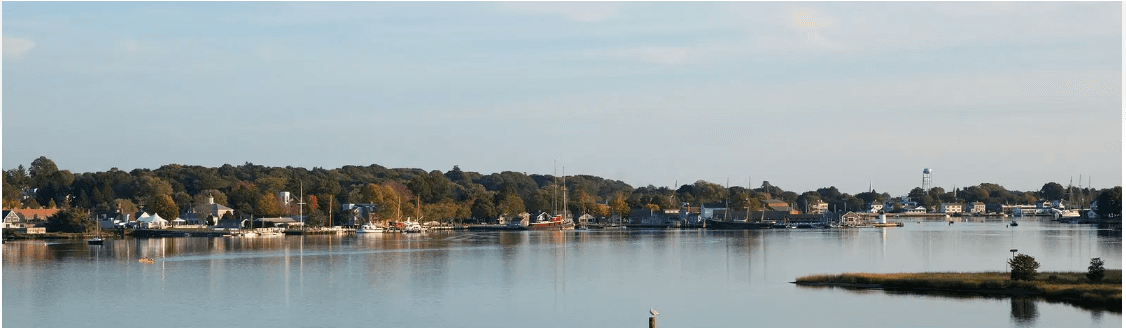 A tranquil waterfront scene featuring a marina and colorful autumn foliage.