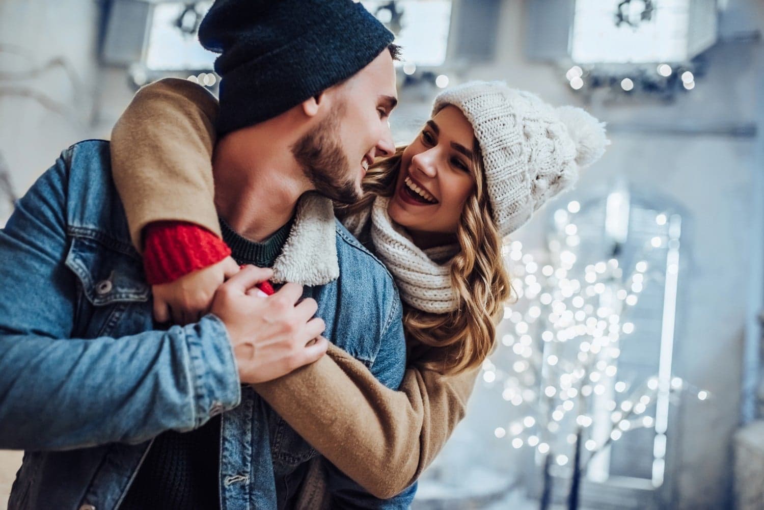 A happy couple embraces in a cozy, festive setting with twinkling lights. A happy couple embraces in a cozy, festive setting with twinkling lights.