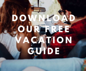A couple sitting in a car looks at a map, with a text overlay promoting a free vacation guide.