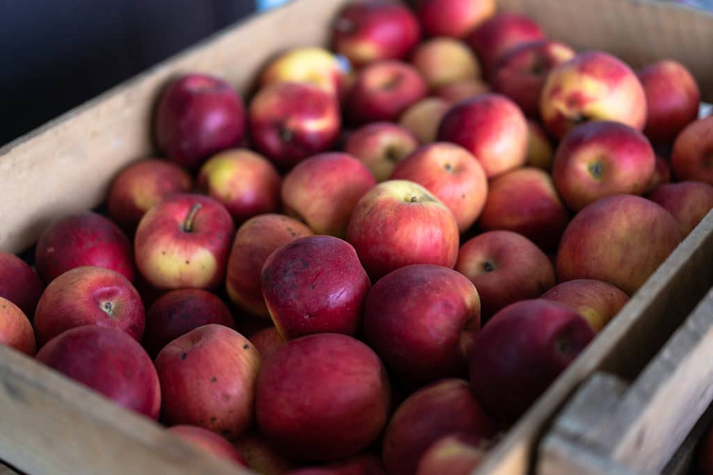 A wooden crate filled with assorted red apples.