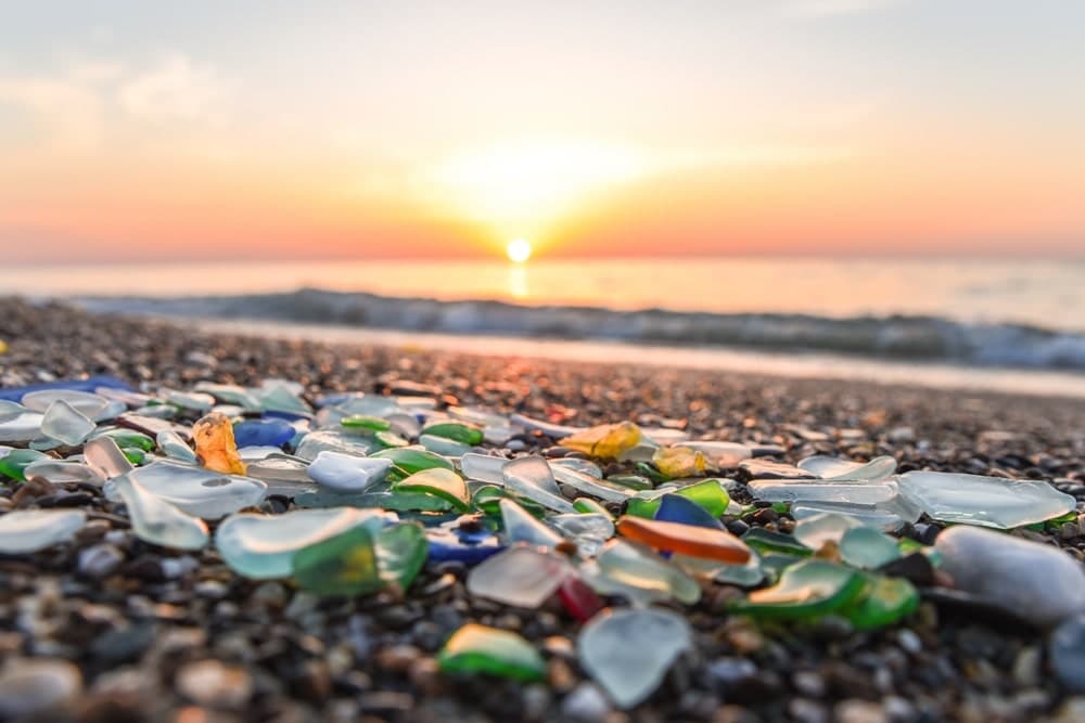 Colorful sea glass scattered along a beach at sunset.