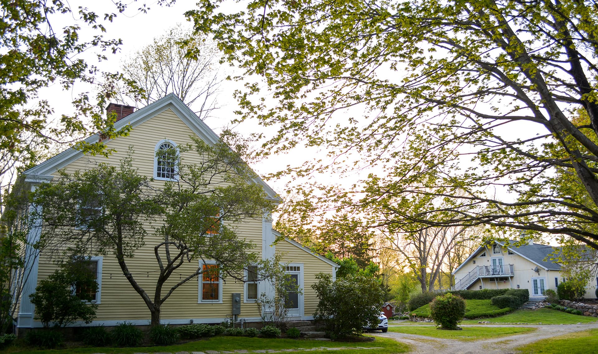 A yellow house surrounded by trees at sunset.