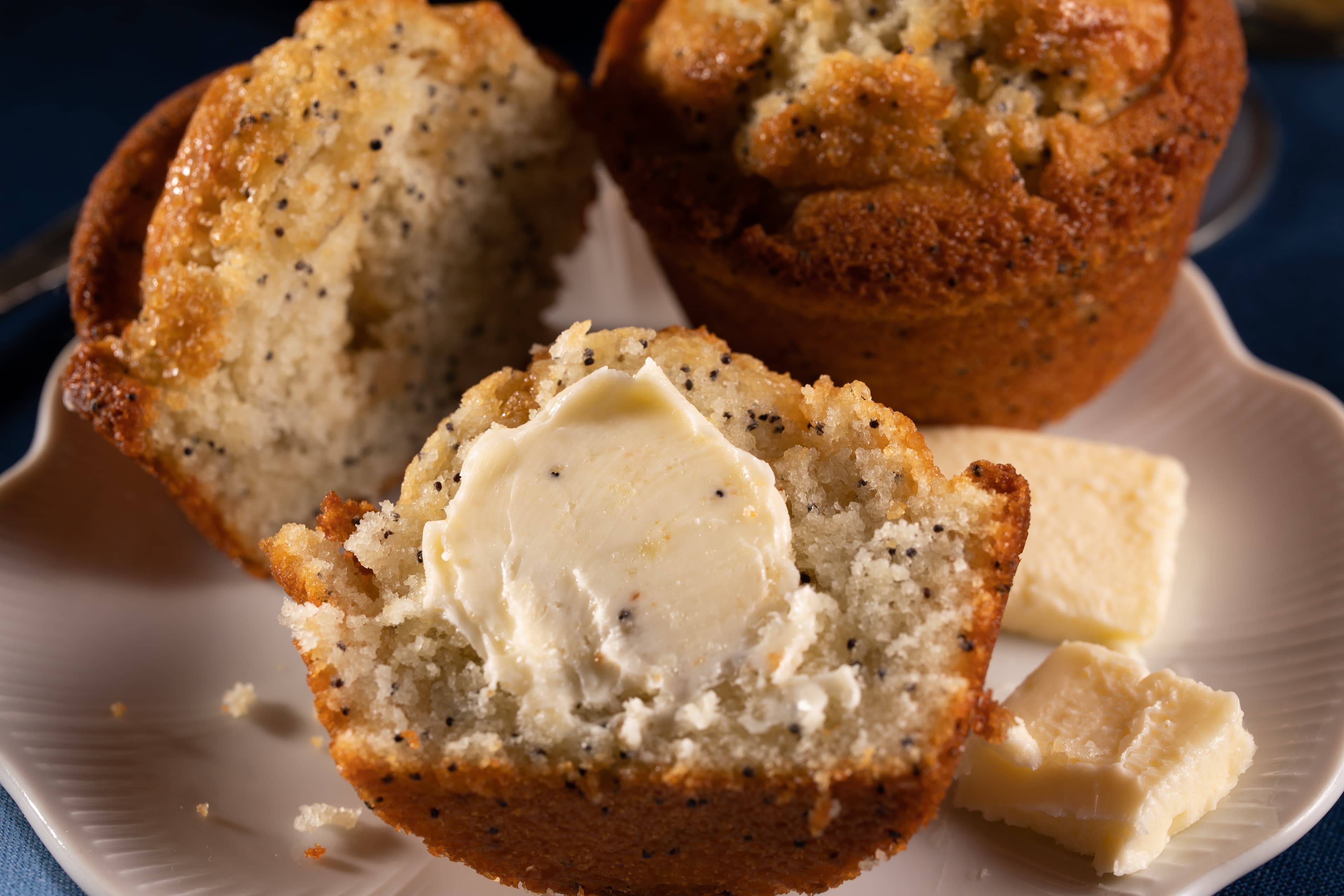 A freshly baked muffin with a buttery center, served with cubes of butter on the side.
