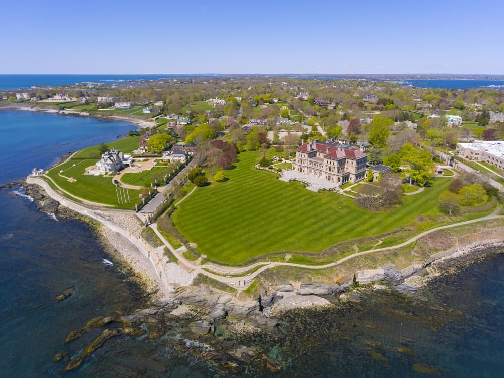 Aerial view of a coastal estate surrounded by lush greenery and ocean waves.