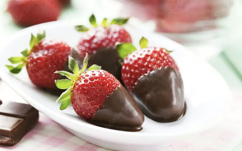 A small dish holds four chocolate-dipped strawberries.