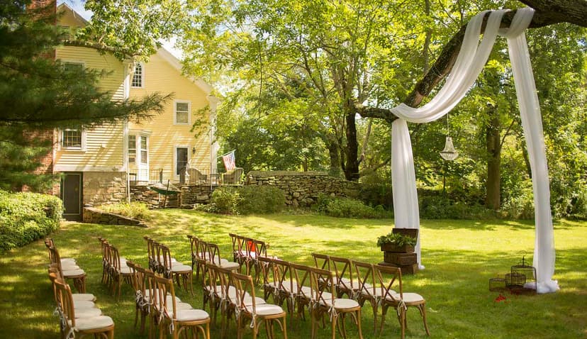 chairs set up for an outdoor wedding on a summer day in green grass with a yellow barn in the background