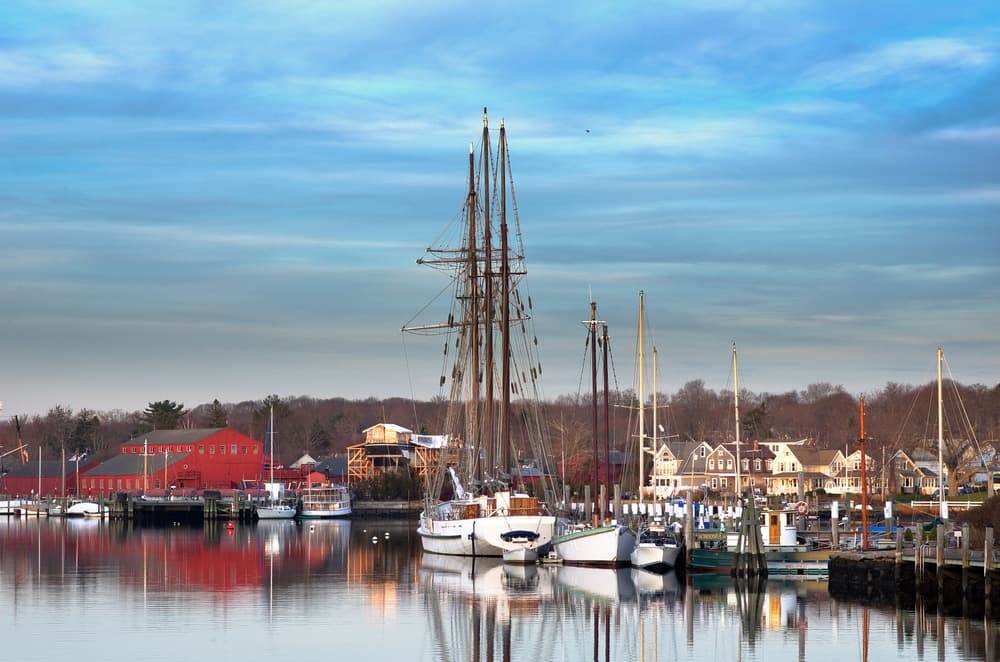 A tranquil harbor scene featuring sailboats and a red building under a blue sky.