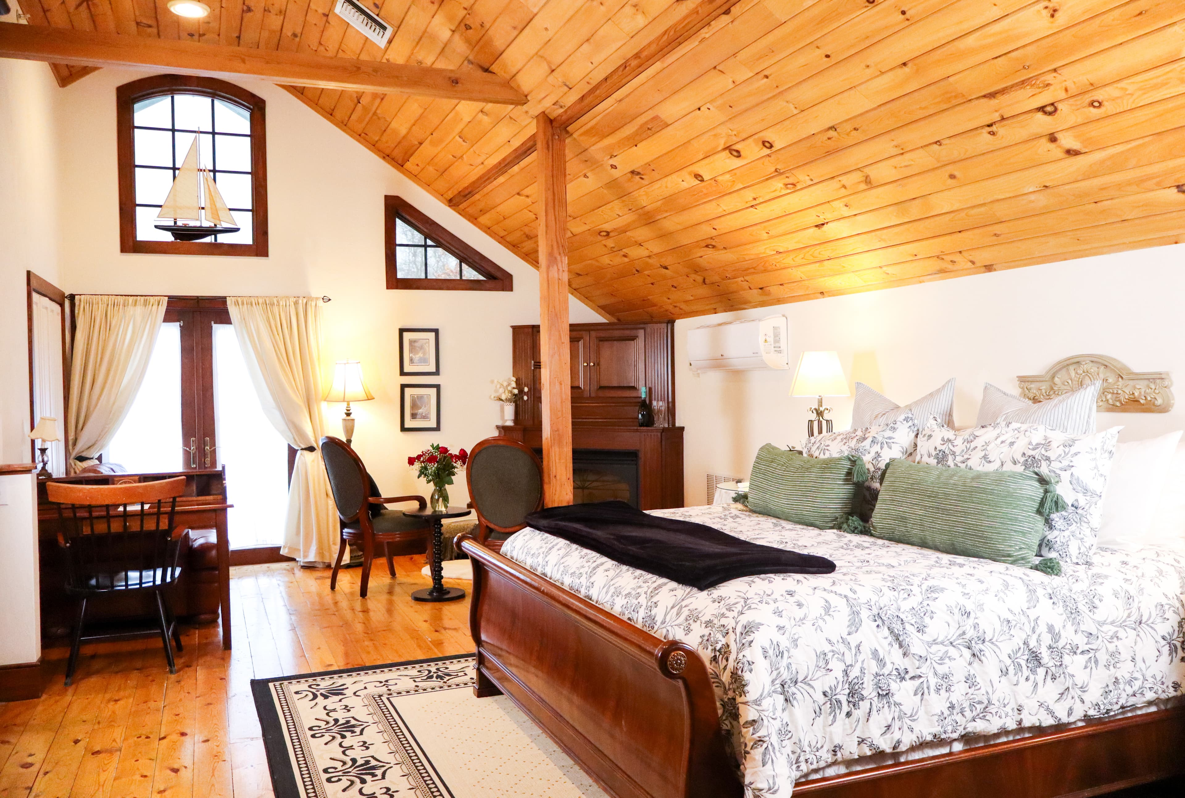 Cozy bedroom with a wooden ceiling, elegant bed, and a small workspace near the window.