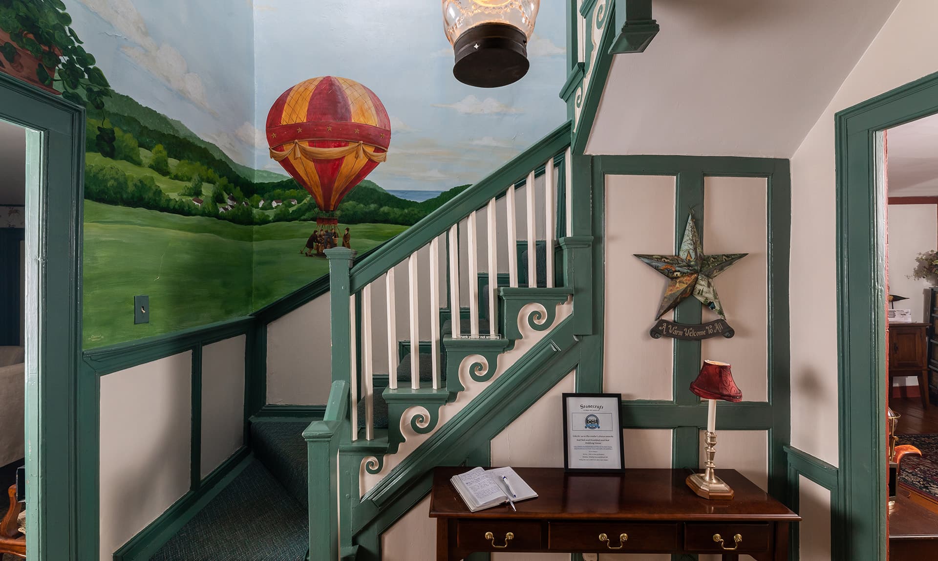 A colorful hot air balloon mural decorates the wall above a staircase leading to an inviting hallway.