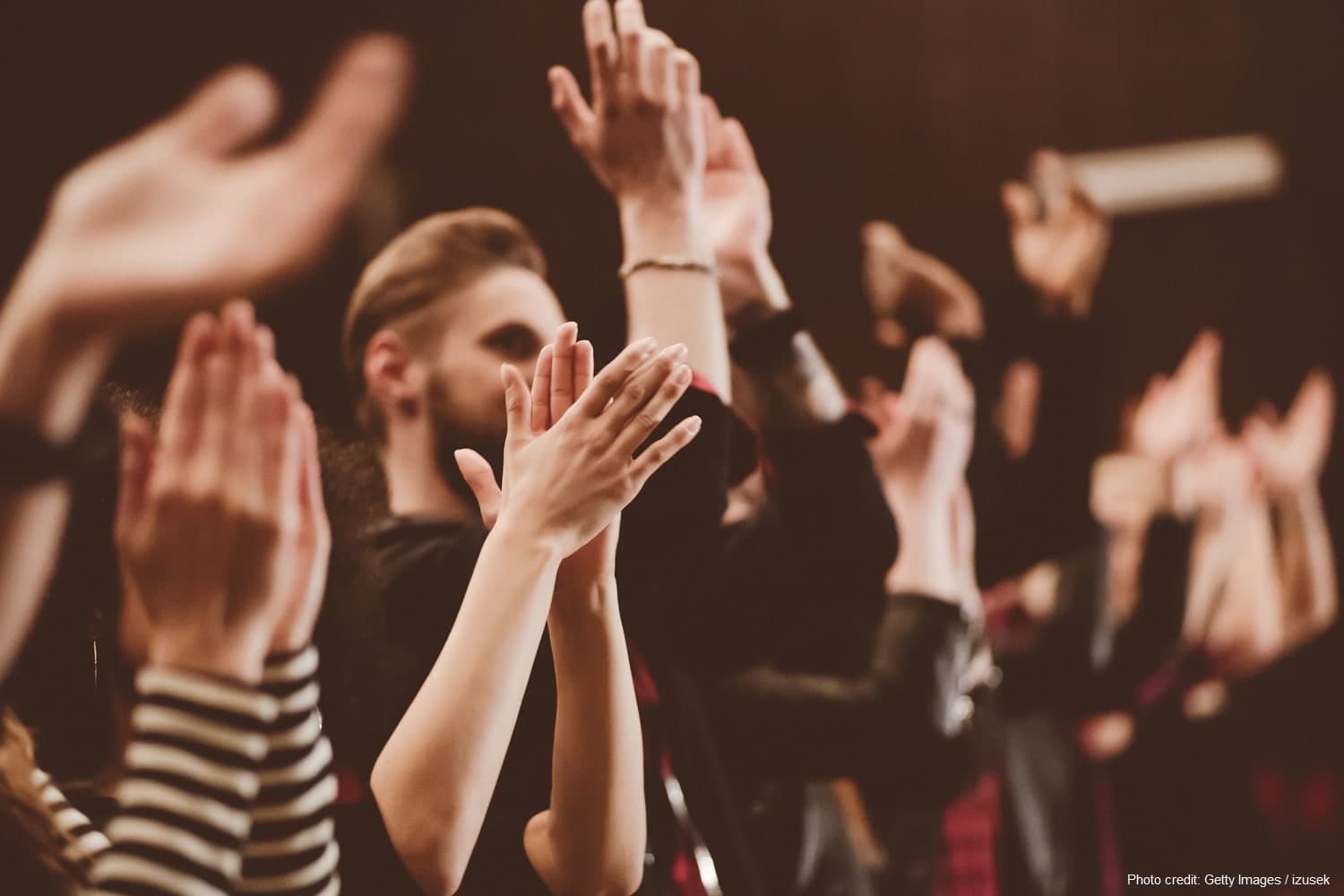 A crowd applauding enthusiastically, with hands raised in celebration.