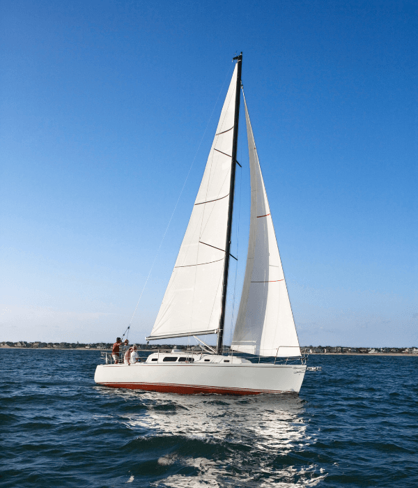 A sailboat glides across the water under a clear blue sky.