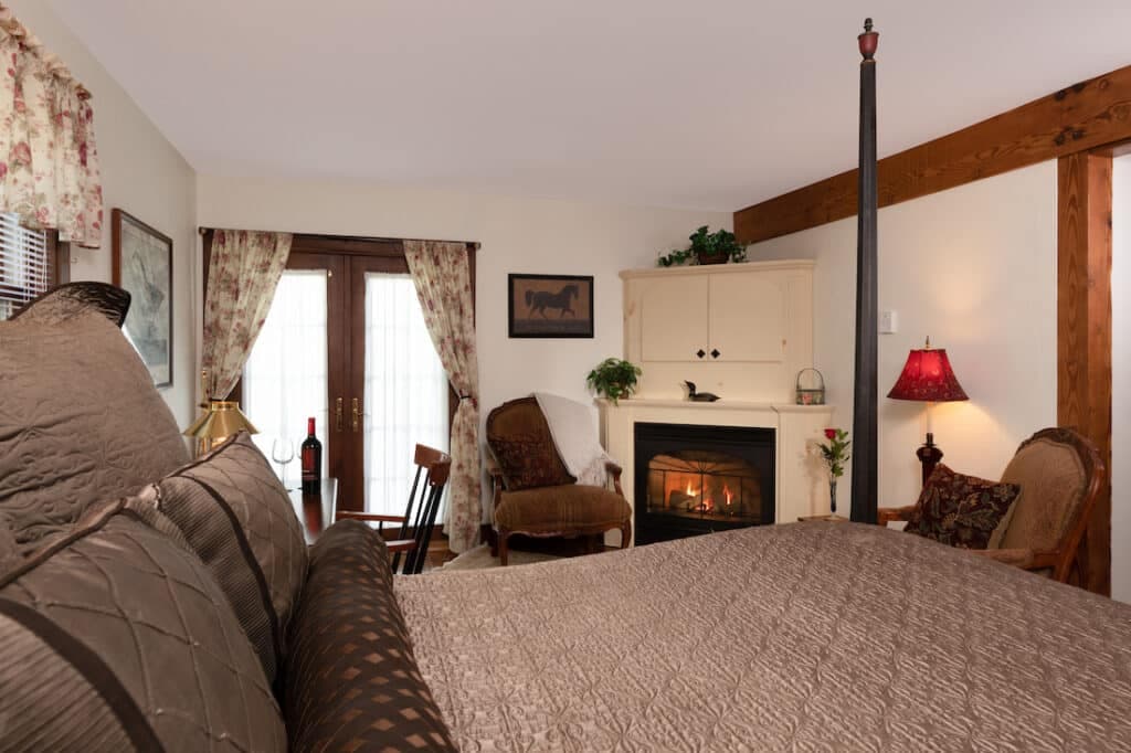 Cozy bedroom featuring a four-poster bed, a fireplace, and comfortable seating by the window.
