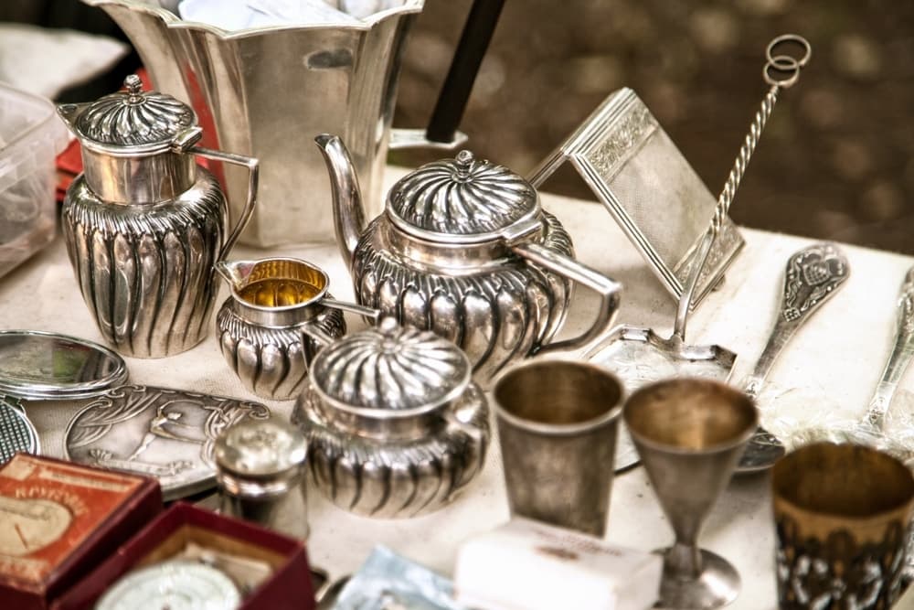 A collection of ornate silver teapots and cups displayed on a table.