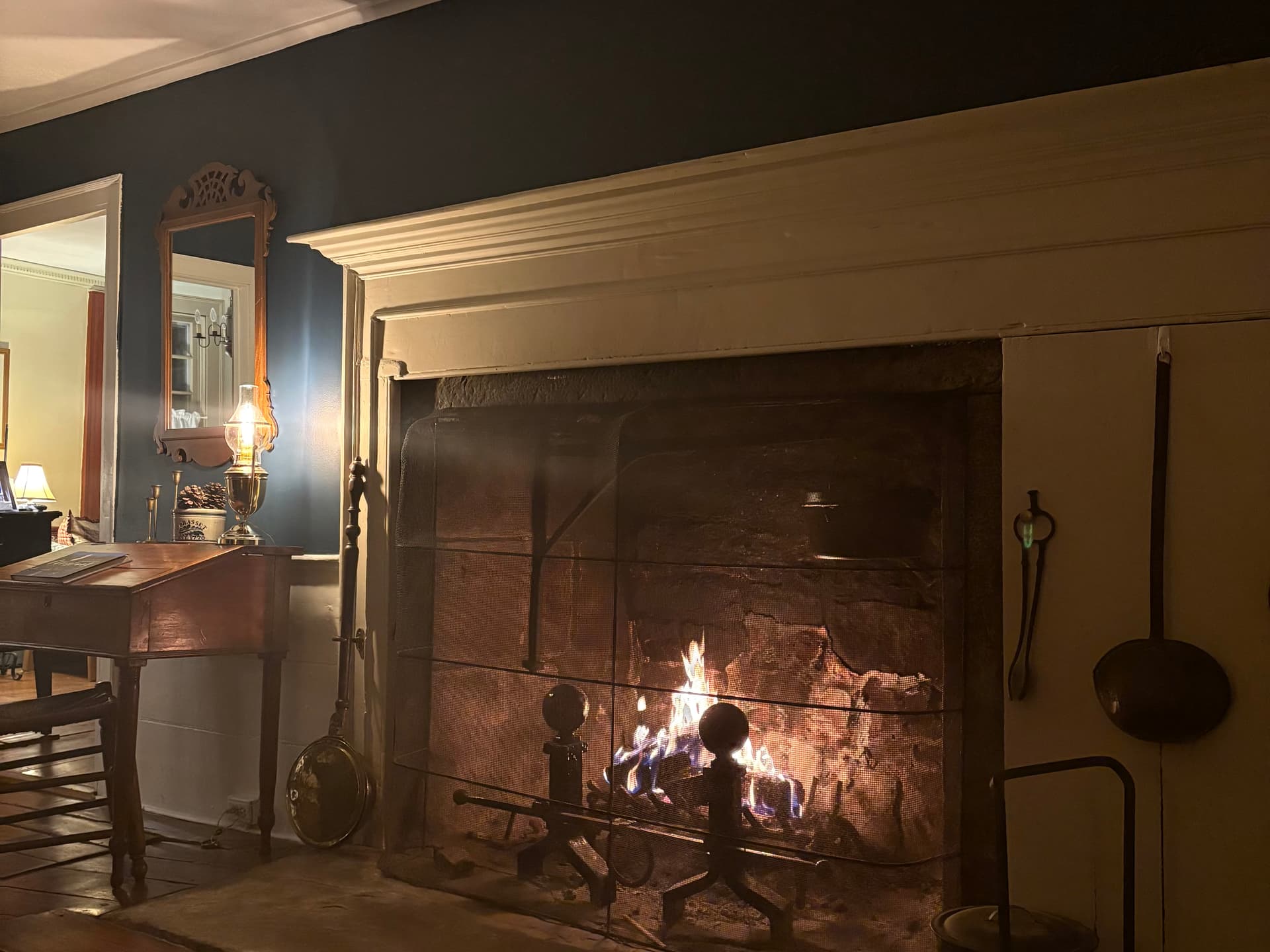 Wood burning fireplace surrounded by a stone hearth in an 1800s parlor